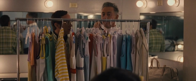 Wide shot frame from Battle of the Sexes — standing, mirror, face