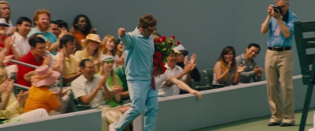 Wide shot frame from Battle of the Sexes — standing, hat, hand