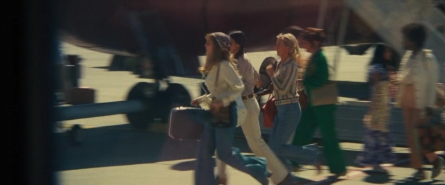 Wide shot frame from Battle of the Sexes — walking, suitcase, airplane