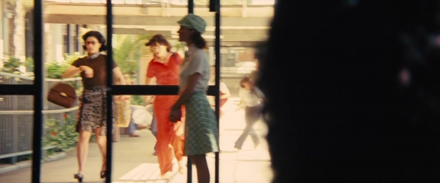 Wide shot frame from Battle of the Sexes — walking, street, hat