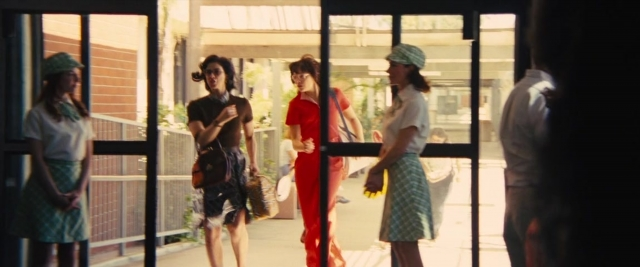 Wide shot frame from Battle of the Sexes — standing, dialogue, door