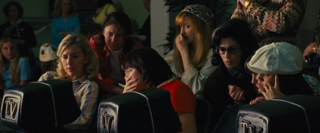 Wide shot frame from Battle of the Sexes — sitting, dialogue, hat