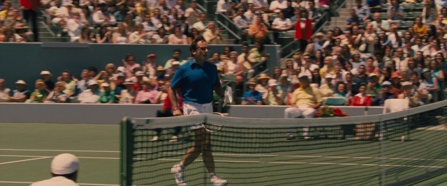 Wide shot frame from Battle of the Sexes — sitting, standing, hand