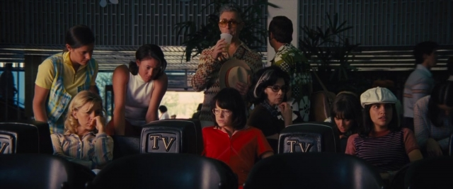 Wide shot frame from Battle of the Sexes — sitting, standing, hat