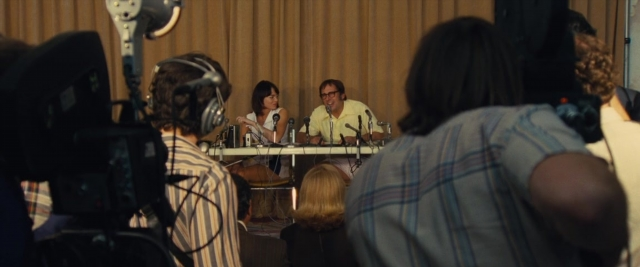 Wide shot frame from Battle of the Sexes — sitting, room, table