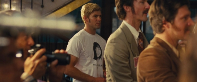Wide shot frame from Battle of the Sexes — standing, room, suit