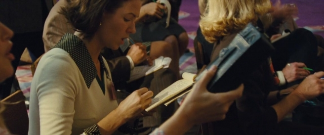 Wide shot frame from Battle of the Sexes — sitting, book, room