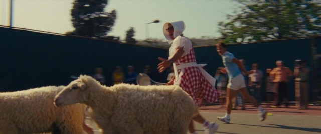 Wide shot frame from Battle of the Sexes — dress, sheep, person