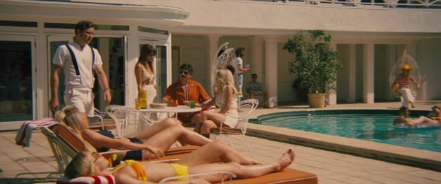 Wide shot frame from Battle of the Sexes — sitting, standing, hand