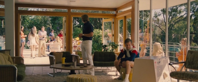 Wide shot frame from Battle of the Sexes — sitting, standing, room