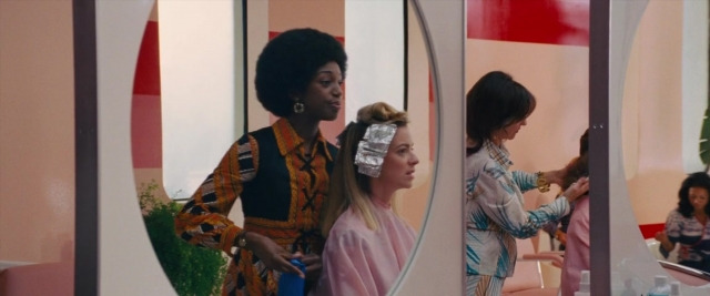 Medium shot frame from Battle of the Sexes — standing, room, table