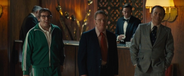 Wide shot frame from Battle of the Sexes — standing, room, suit