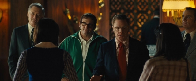 Wide shot frame from Battle of the Sexes — standing, room, suit