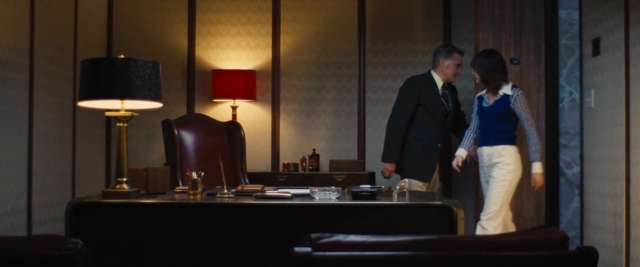 Wide shot frame from Battle of the Sexes — desk, standing, dialogue