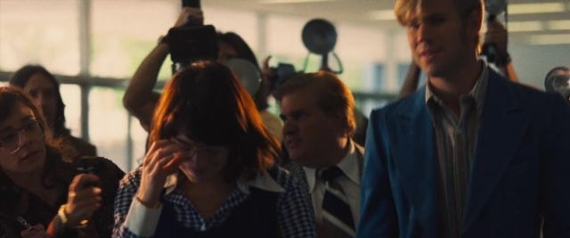 Wide shot frame from Battle of the Sexes — standing, room, suit
