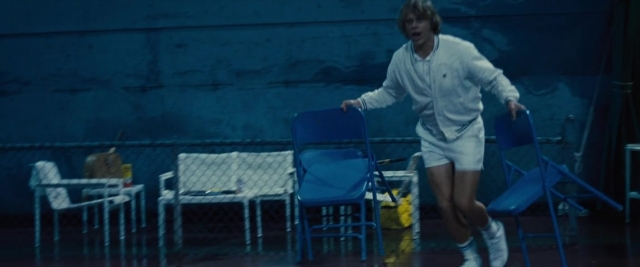 Wide shot frame from Battle of the Sexes — walking, chair, face
