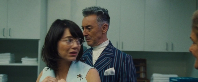 Wide shot frame from Battle of the Sexes — kitchen, suit, dress