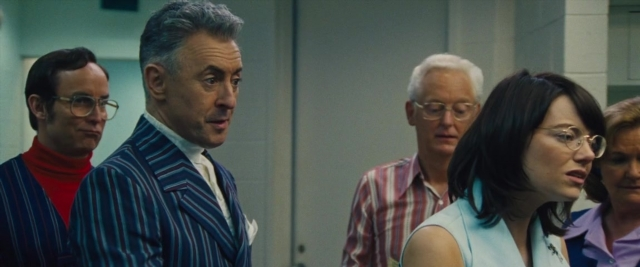 Wide shot frame from Battle of the Sexes — standing, room, suit