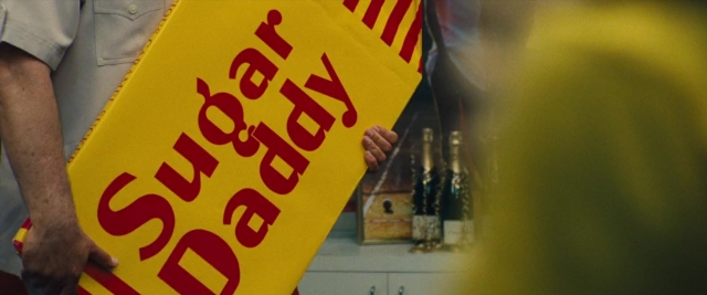 Wide shot frame from Battle of the Sexes — kitchen, hand, shirt