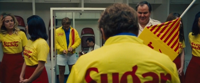 Wide shot frame from Battle of the Sexes — sitting, standing, room