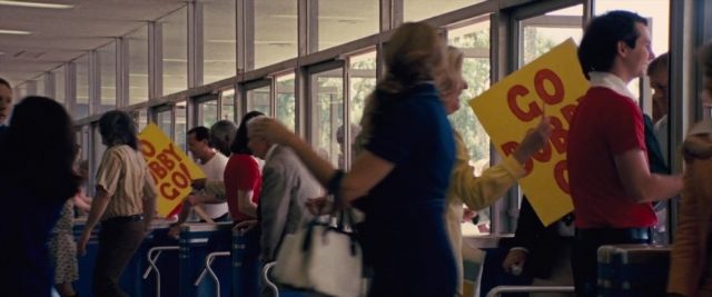 Wide shot frame from Battle of the Sexes — standing, train, person