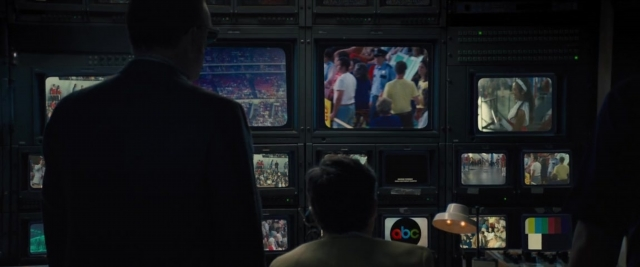 Wide shot frame from Battle of the Sexes — sitting, standing, room