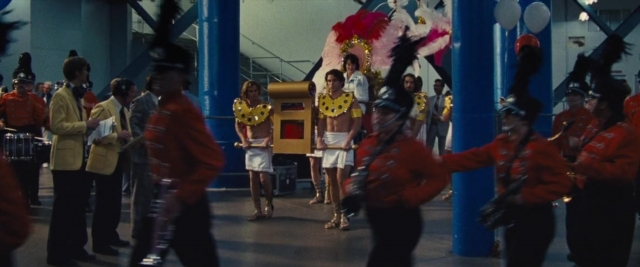 Wide shot frame from Battle of the Sexes — standing, hat, suit