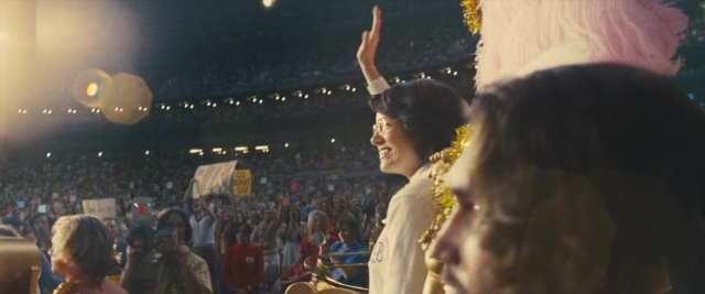 Wide shot frame from Battle of the Sexes — hat, hand, night