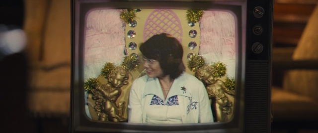 Wide shot frame from Battle of the Sexes — sitting, room, television