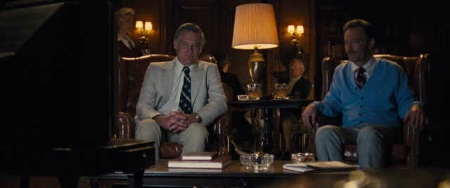 Wide shot frame from Battle of the Sexes — sitting, standing, room