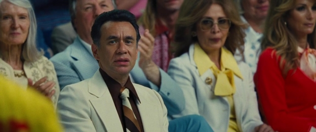Wide shot frame from Battle of the Sexes — sitting, suit, tie