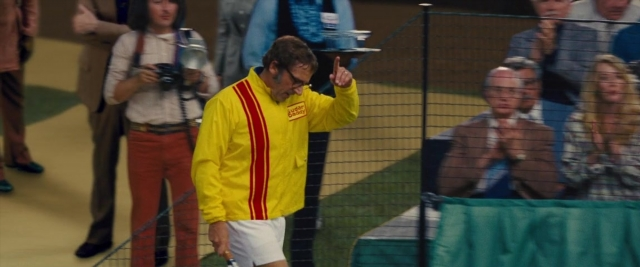 Wide shot frame from Battle of the Sexes — sitting, standing, hand