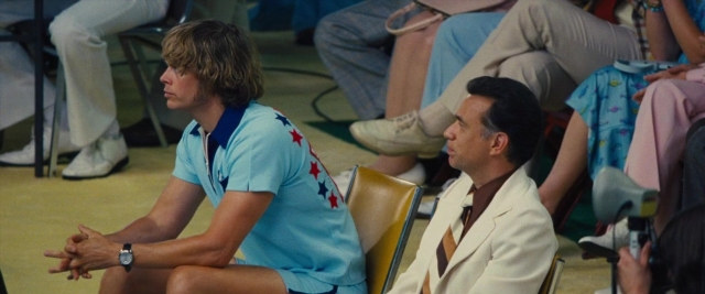 Wide shot frame from Battle of the Sexes — sitting, standing, room