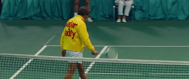 Frame from Battle of the Sexes — sitting, standing, hand