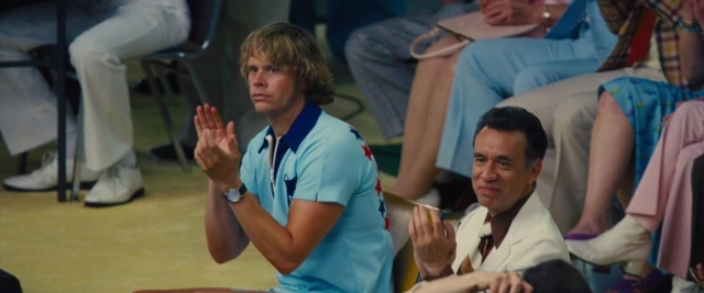 Wide shot frame from Battle of the Sexes — sitting, standing, room