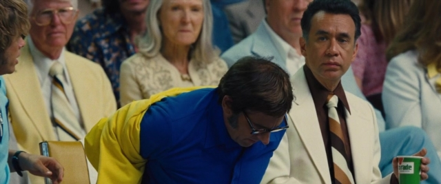 Wide shot frame from Battle of the Sexes — sitting, room, suit