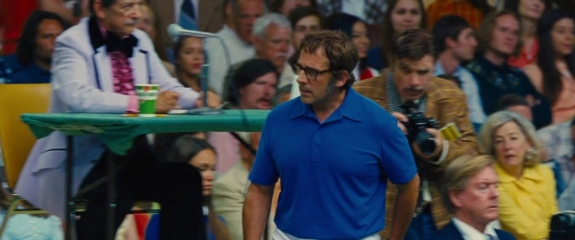 Wide shot frame from Battle of the Sexes — standing, table, dialogue