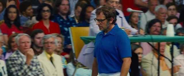 Wide shot frame from Battle of the Sexes — standing, table, dialogue