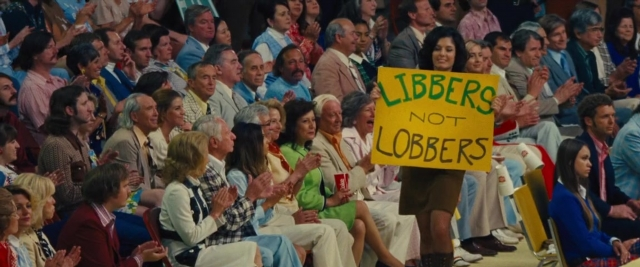 Wide shot frame from Battle of the Sexes — sitting, standing, dress