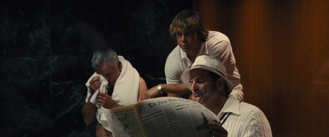 Wide shot frame from Battle of the Sexes — sitting, standing, room