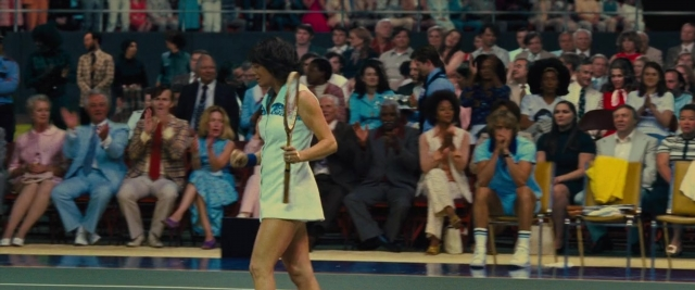 Wide shot frame from Battle of the Sexes — sitting, standing, hand
