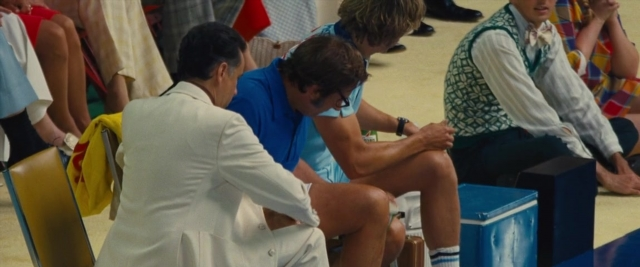 Wide shot frame from Battle of the Sexes — sitting, dialogue, hand