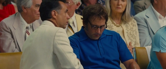 Wide shot frame from Battle of the Sexes — sitting, suit, tie