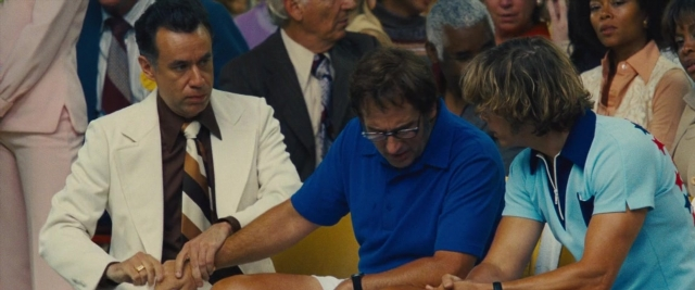 Wide shot frame from Battle of the Sexes — sitting, room, suit