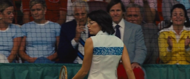 Wide shot frame from Battle of the Sexes — sitting, standing, hand