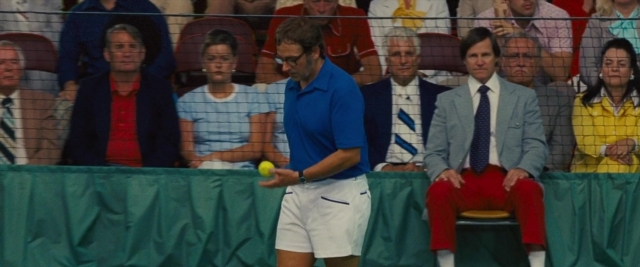 Wide shot frame from Battle of the Sexes — sitting, standing, hand