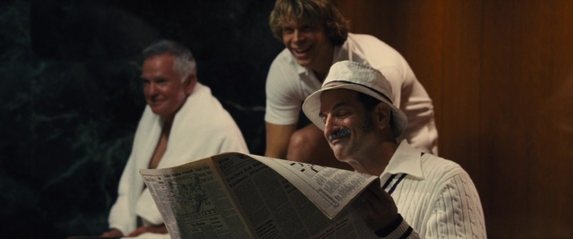 Wide shot frame from Battle of the Sexes — sitting, standing, room