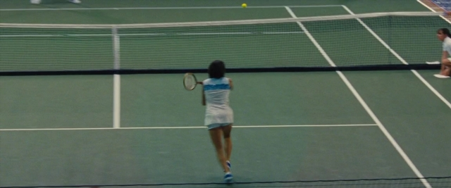 Wide shot frame from Battle of the Sexes — sitting, standing, hand