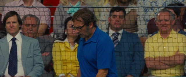Wide shot frame from Battle of the Sexes — sitting, standing, suit