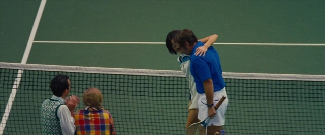 Frame from Battle of the Sexes — standing, dialogue, hand